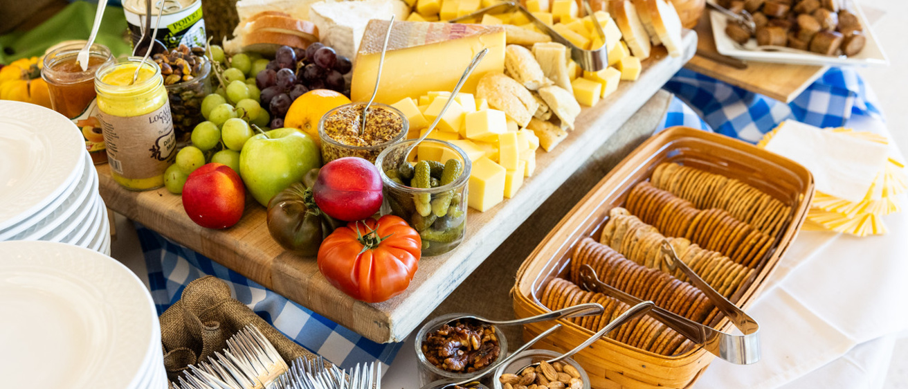A cheese table with fresh vegetables and bread is set up at a Catering event