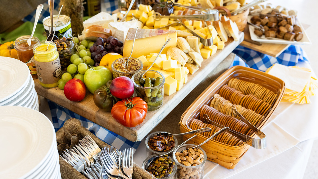 A cheese table with fresh vegetables and bread is set up at a Catering event